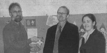 Josef Krickl (l.) und Daniela Hasbauer (r.) überreichen Pfarrer Johannes Trum das Kuratenkreuz. (Foto: privat)